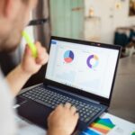 Home Focused adult analyzing charts and graphs on a laptop for business insights.